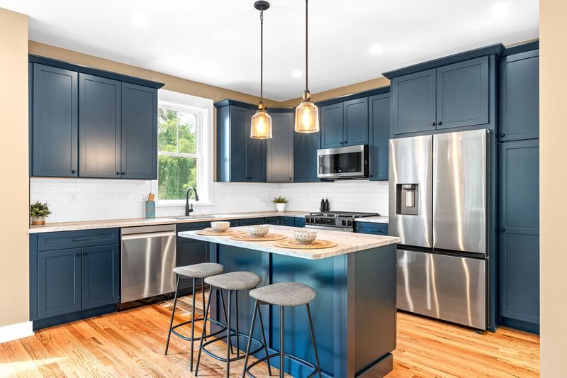 Navy kitchen with pendant lights and stainless appliances