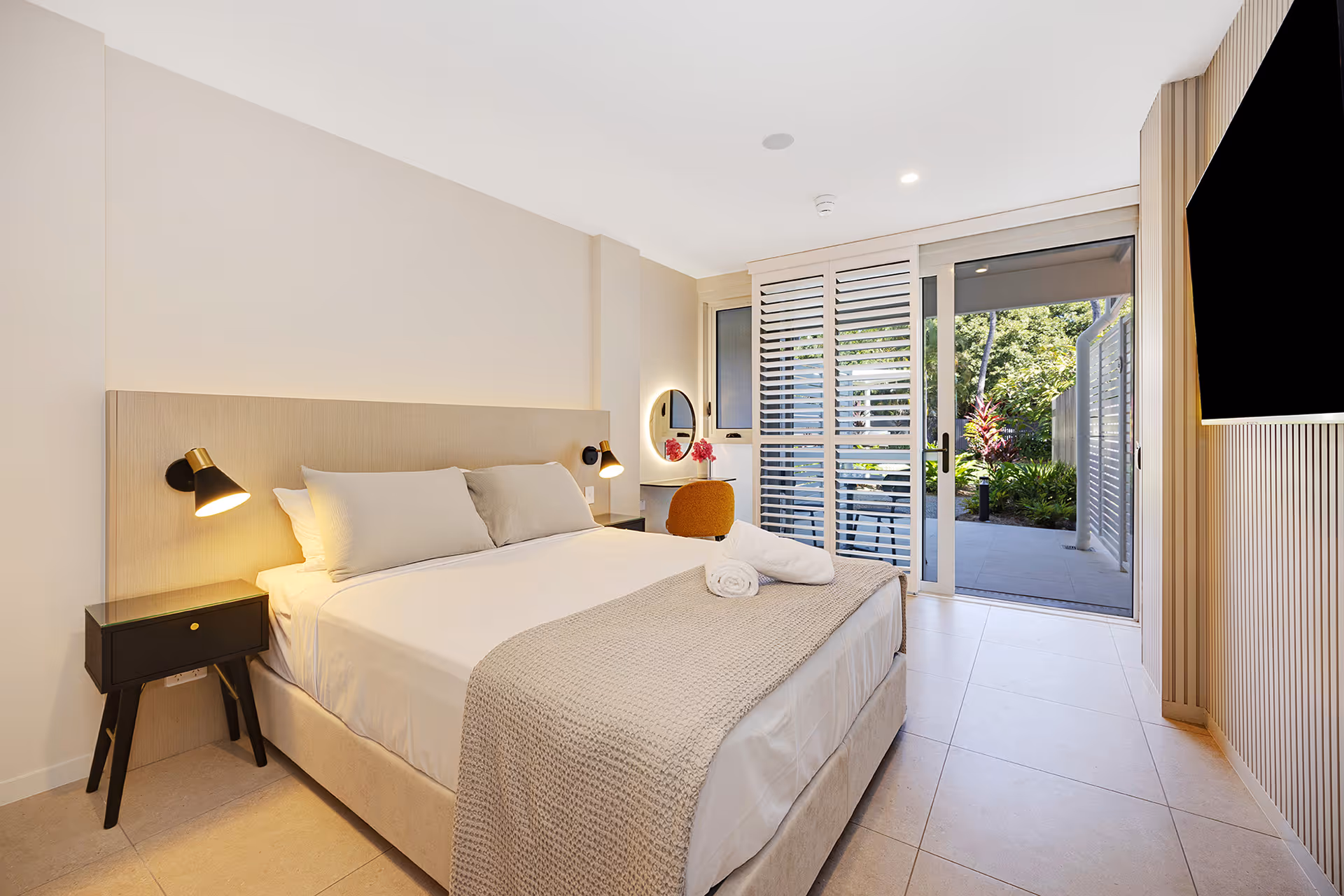 The queen bed in the Garden Queen Room, with doors open to the private courtyard.