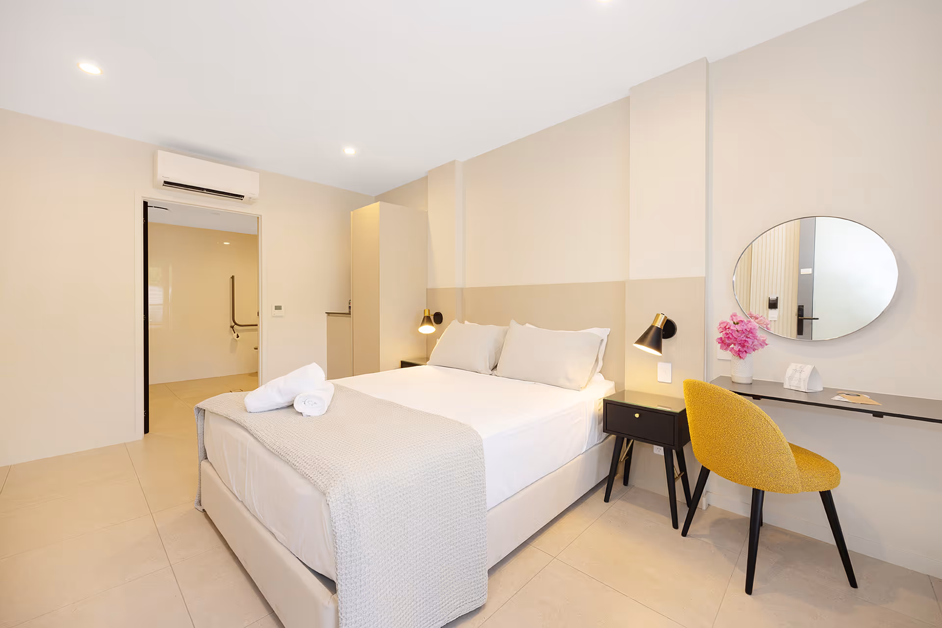 The queen bed in the Garden Accessible Room, with a desk and round mirror.