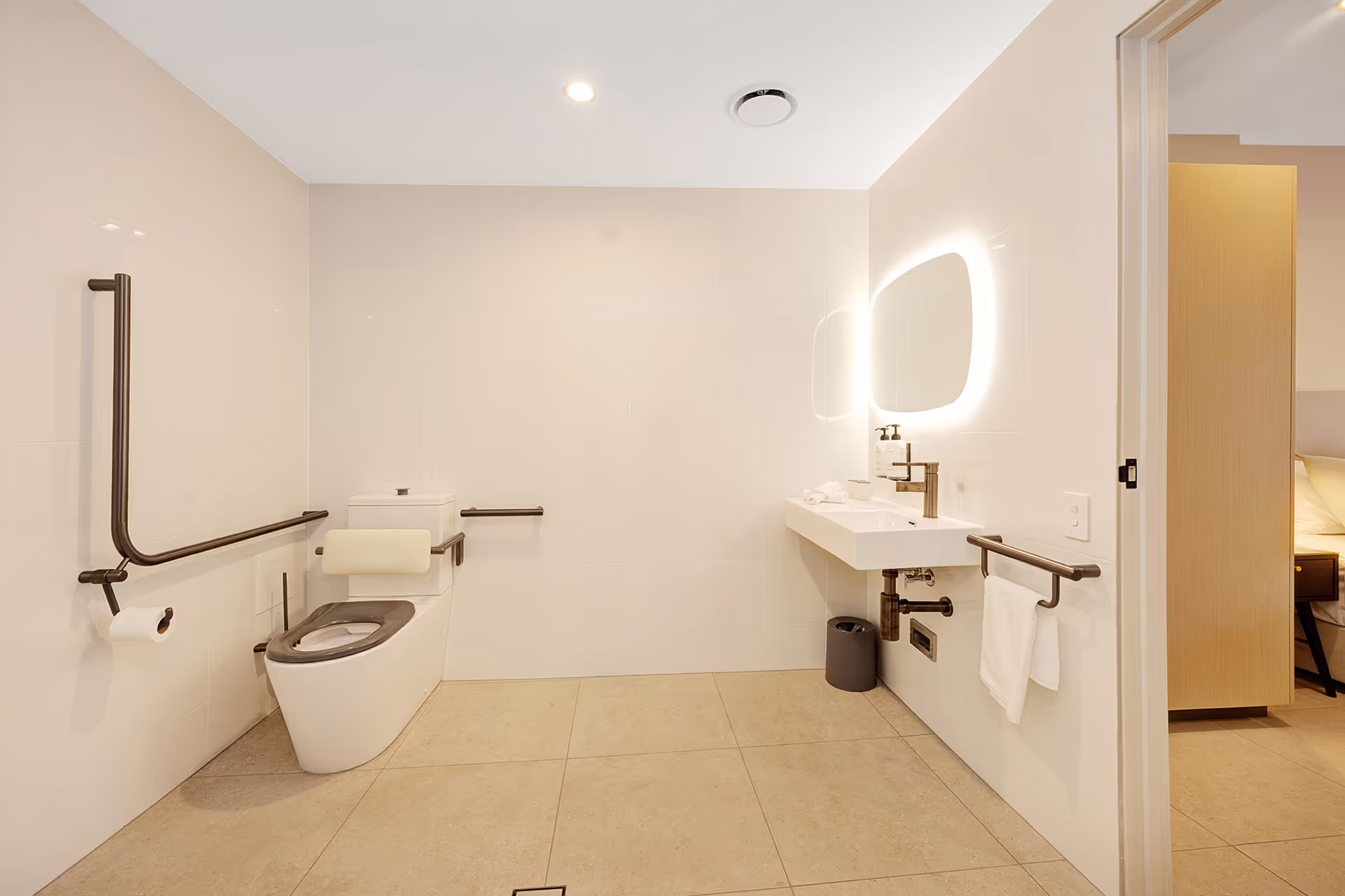 The accessible bathroom, with grab rails beside the toilet and basin.