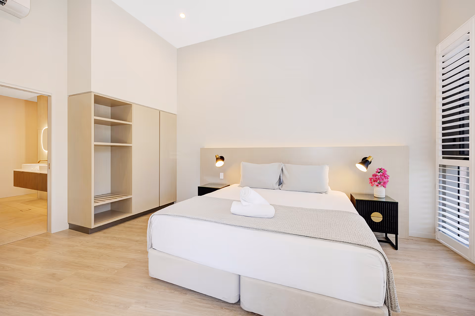 The Executive Suite bedroom, with a king bed and open wardrobe beneath a high vaulted ceiling.
