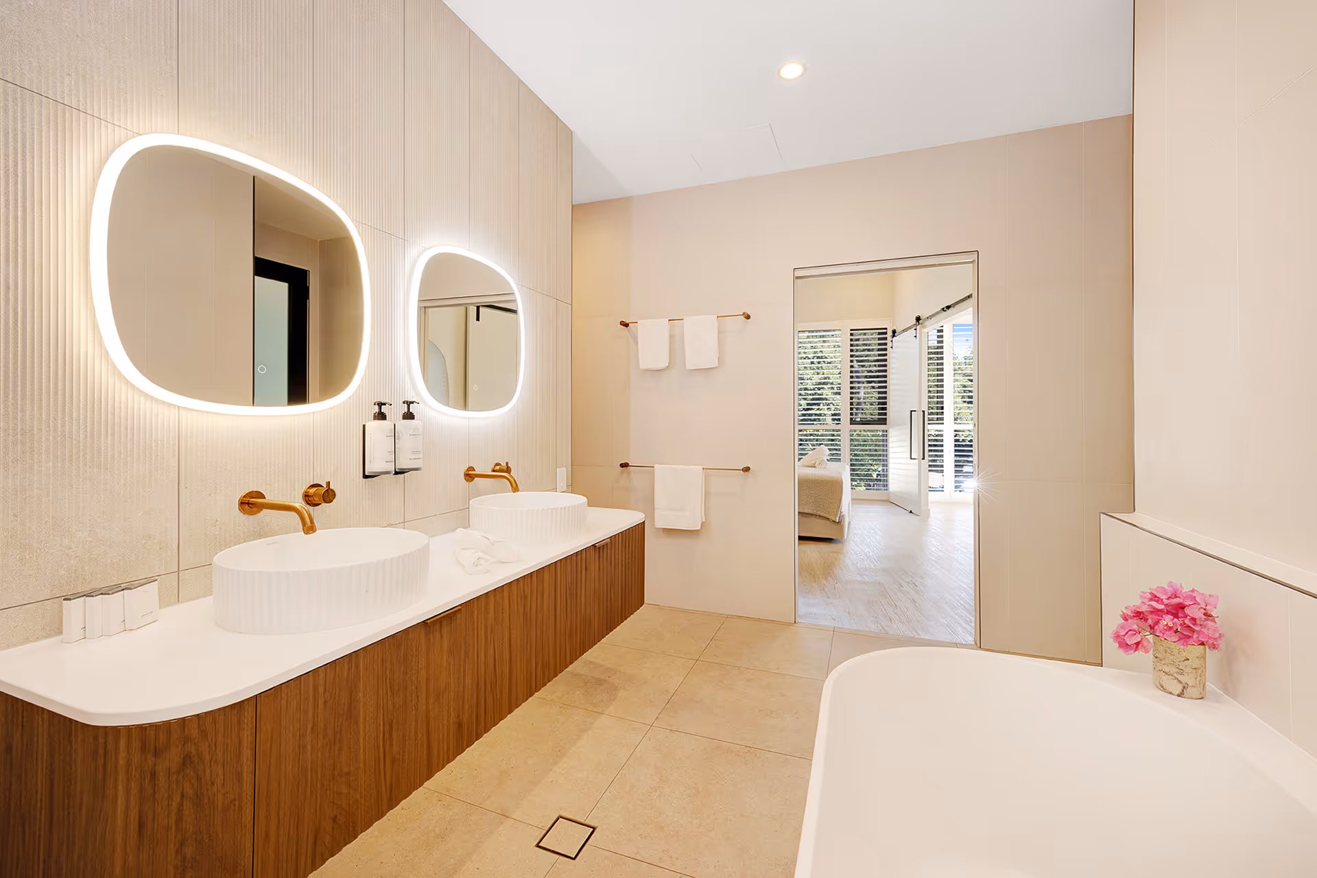 The Executive Suite bathroom, with twin basins, backlit mirrors and a view through to the bedroom.