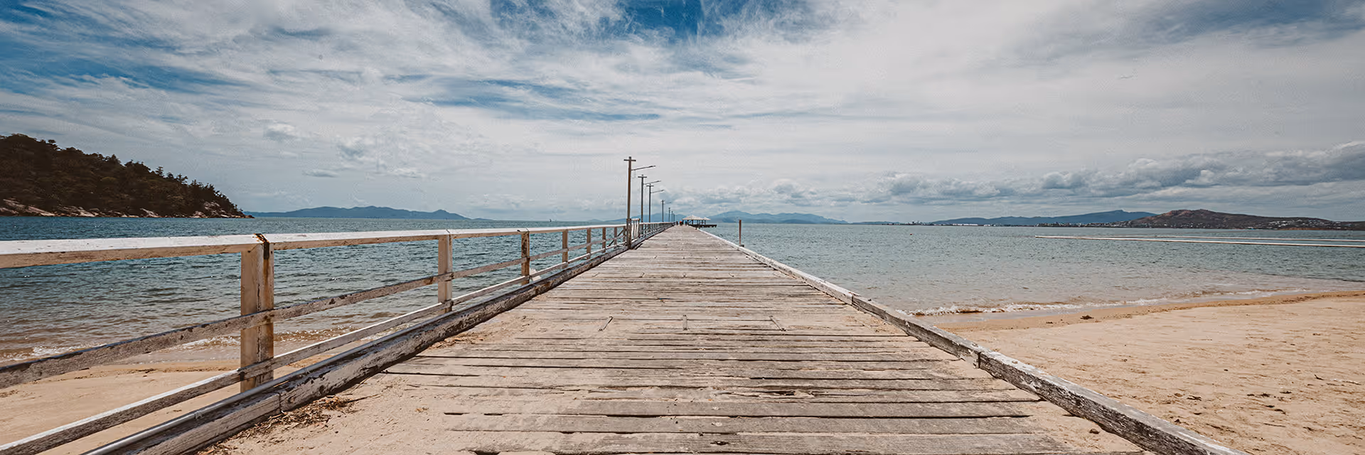 The timber deck of the Picnic Bay jetty stretching out over calm water.