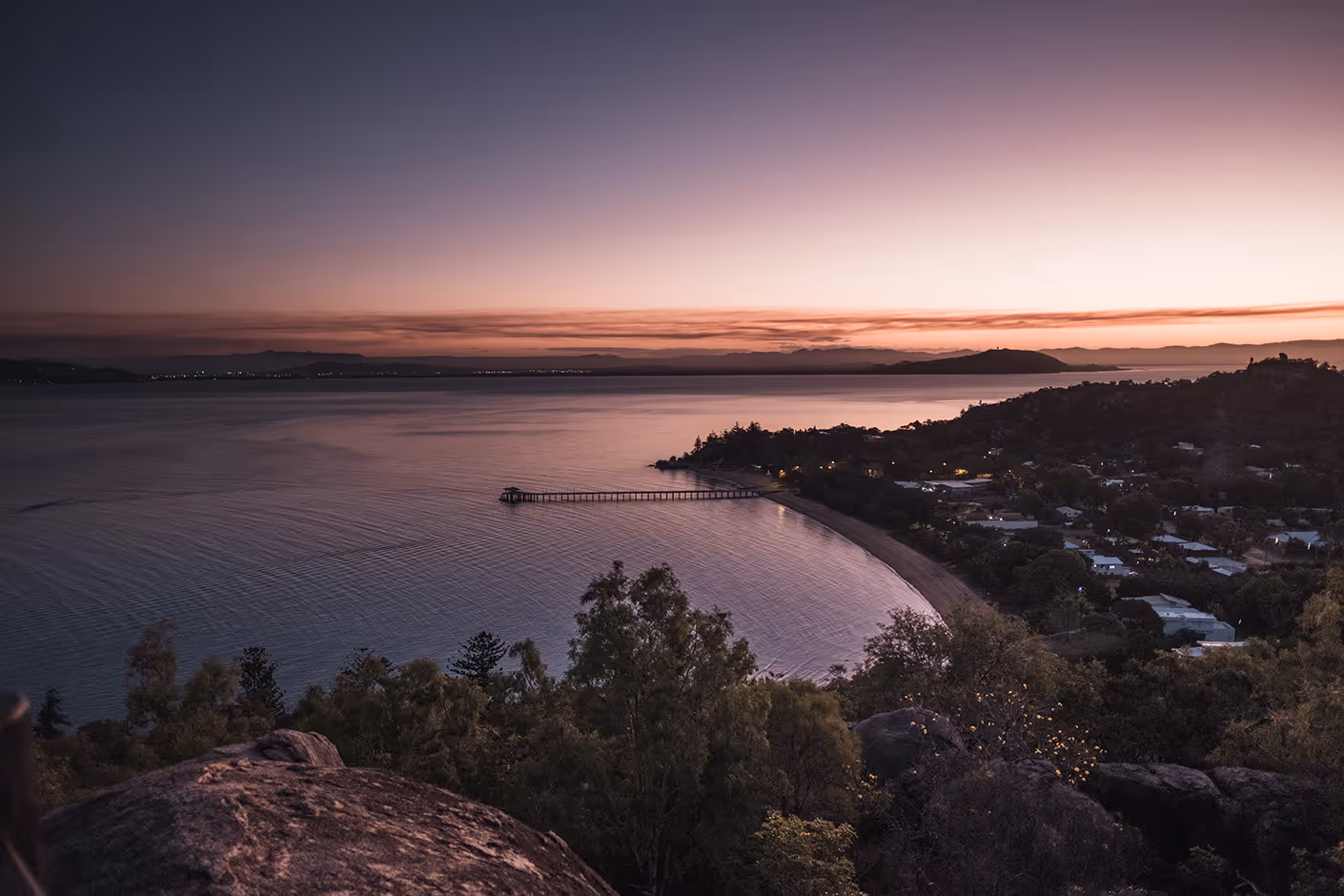 Picnic Bay and its jetty at dusk, the sky turning pink over still water.