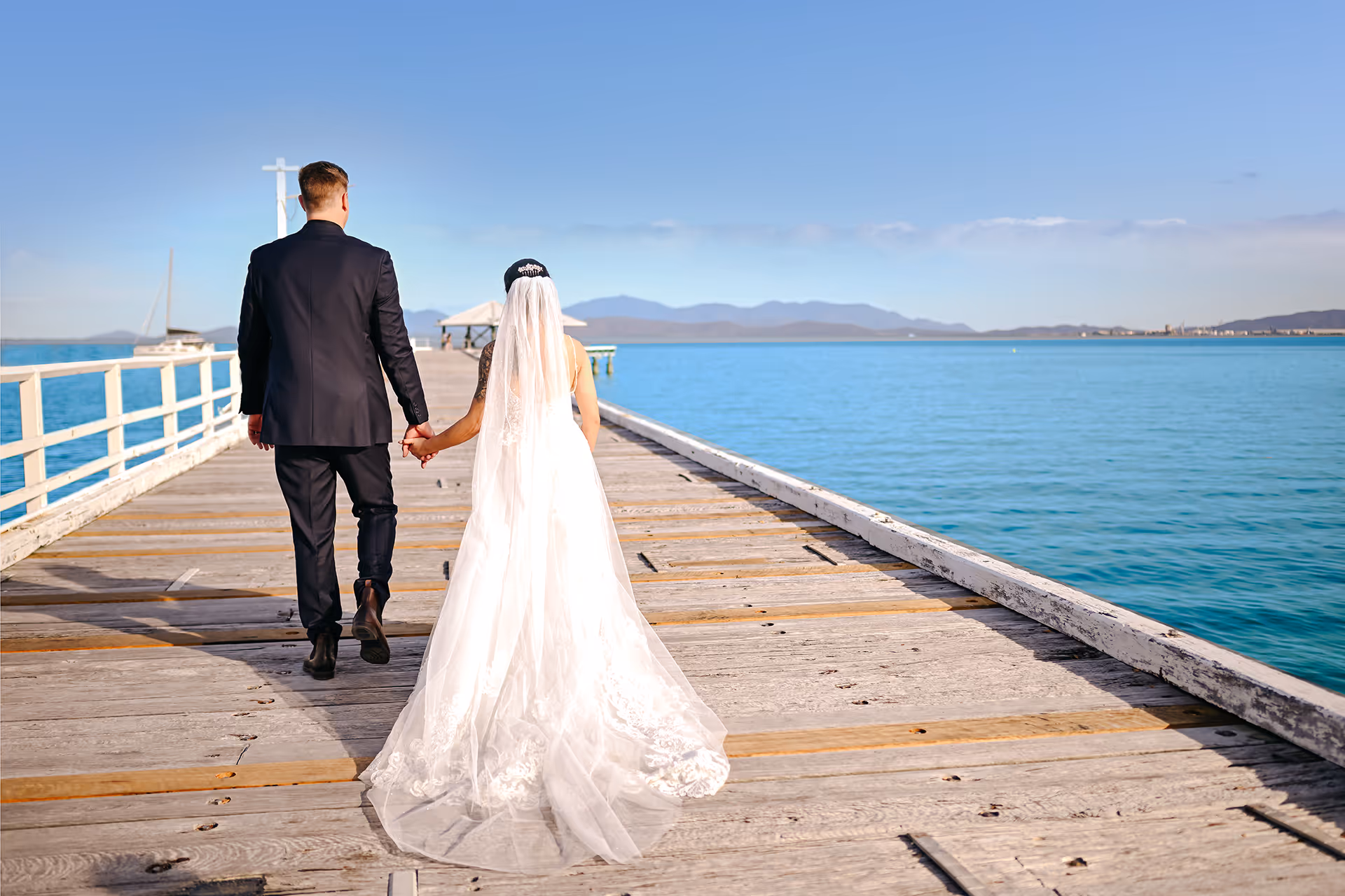 A newly married couple walk hand in hand along the Picnic Bay jetty.
