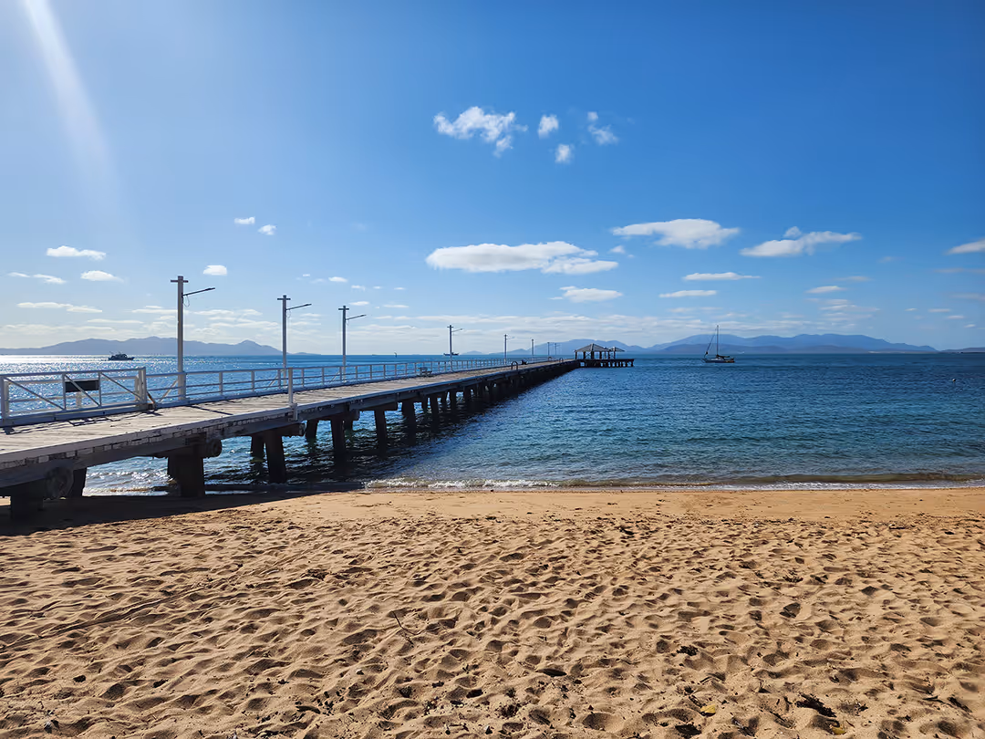 The Picnic Bay jetty seen from the sand on a clear day.