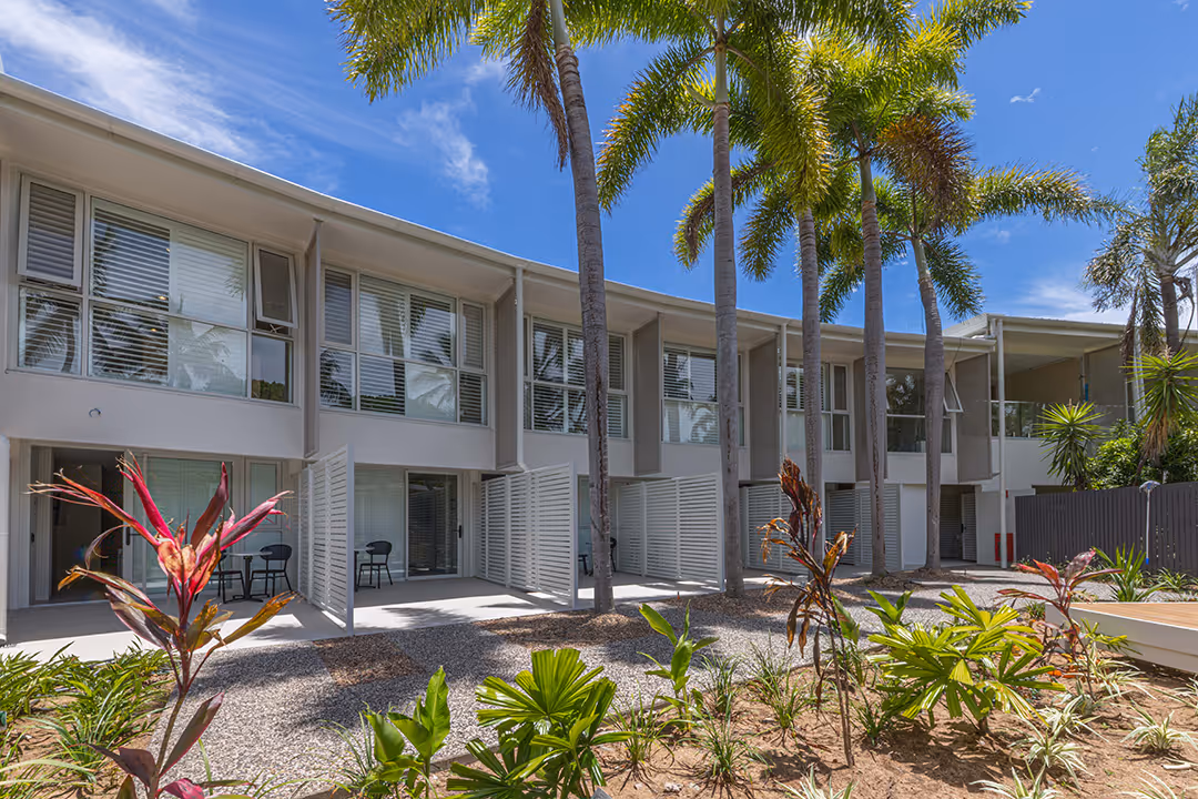 The hotel's garden wing, its curved white facade framed by palms and tropical planting.