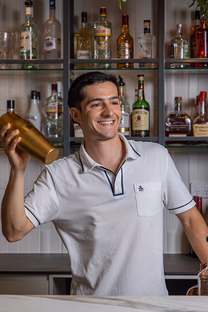 A bartender shakes a cocktail behind the bar.