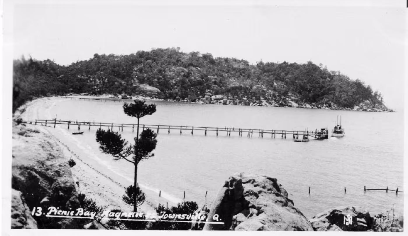 A historic photograph of Picnic Bay and its jetty, looking along the shoreline.