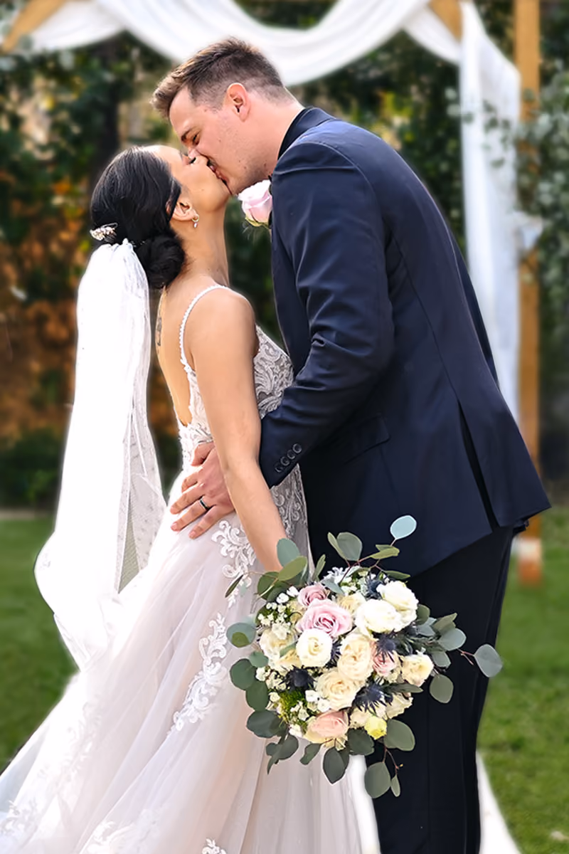A bride and groom embrace after their ceremony, the bride holding a white and blush bouquet.