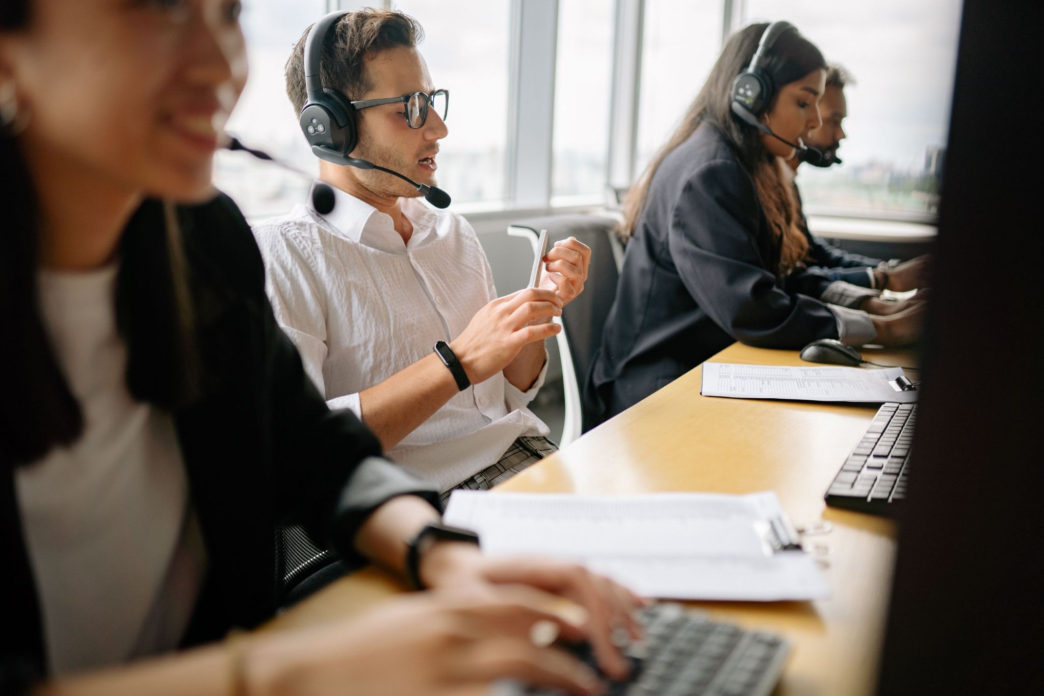 Help desk agents in headsets working side by side at a shared desk