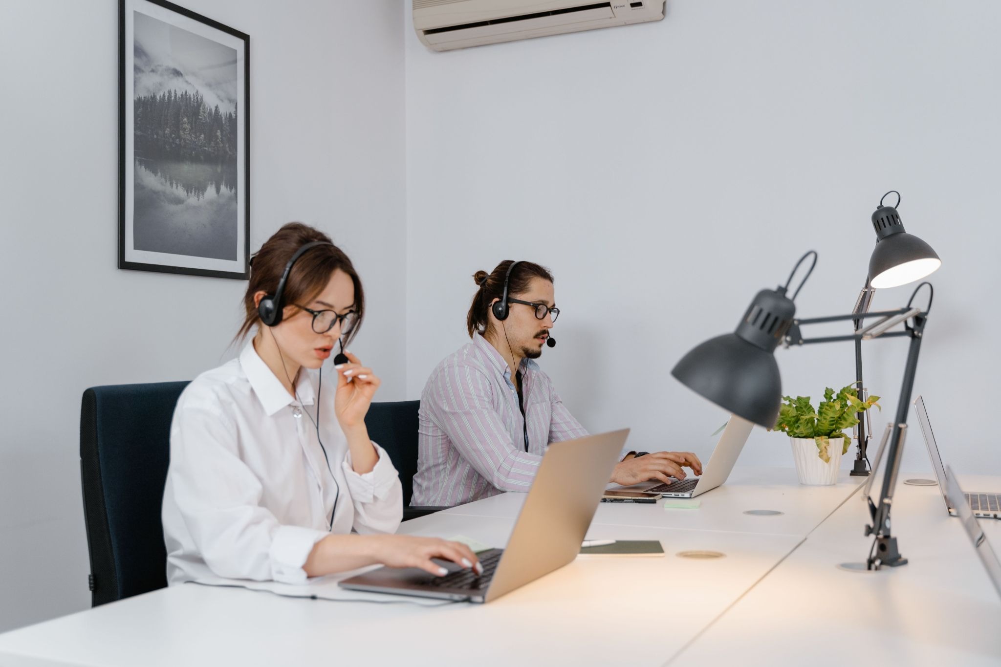 Two support agents in headsets working on laptops