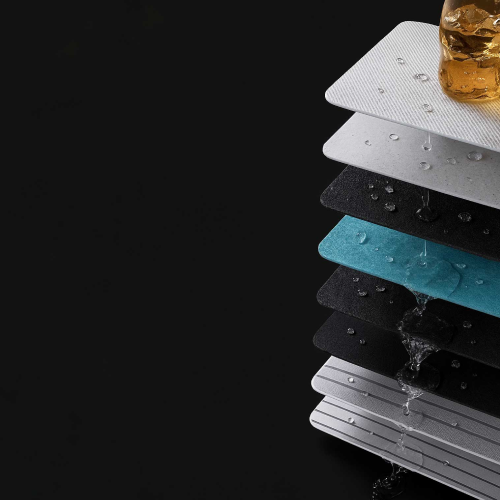 A stack of different fabric or material samples in various colors including white, black, and blue, with water droplets on them and water flowing down the sides against a black background.