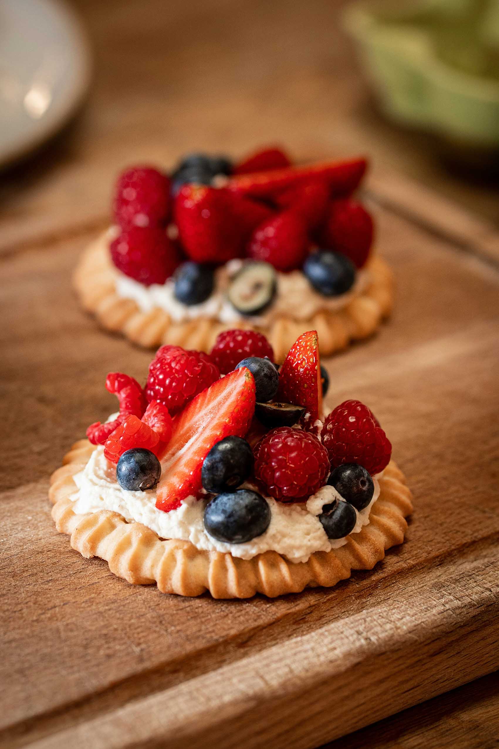 close up of a crostata with cherries and strawberry on a wood chopping board