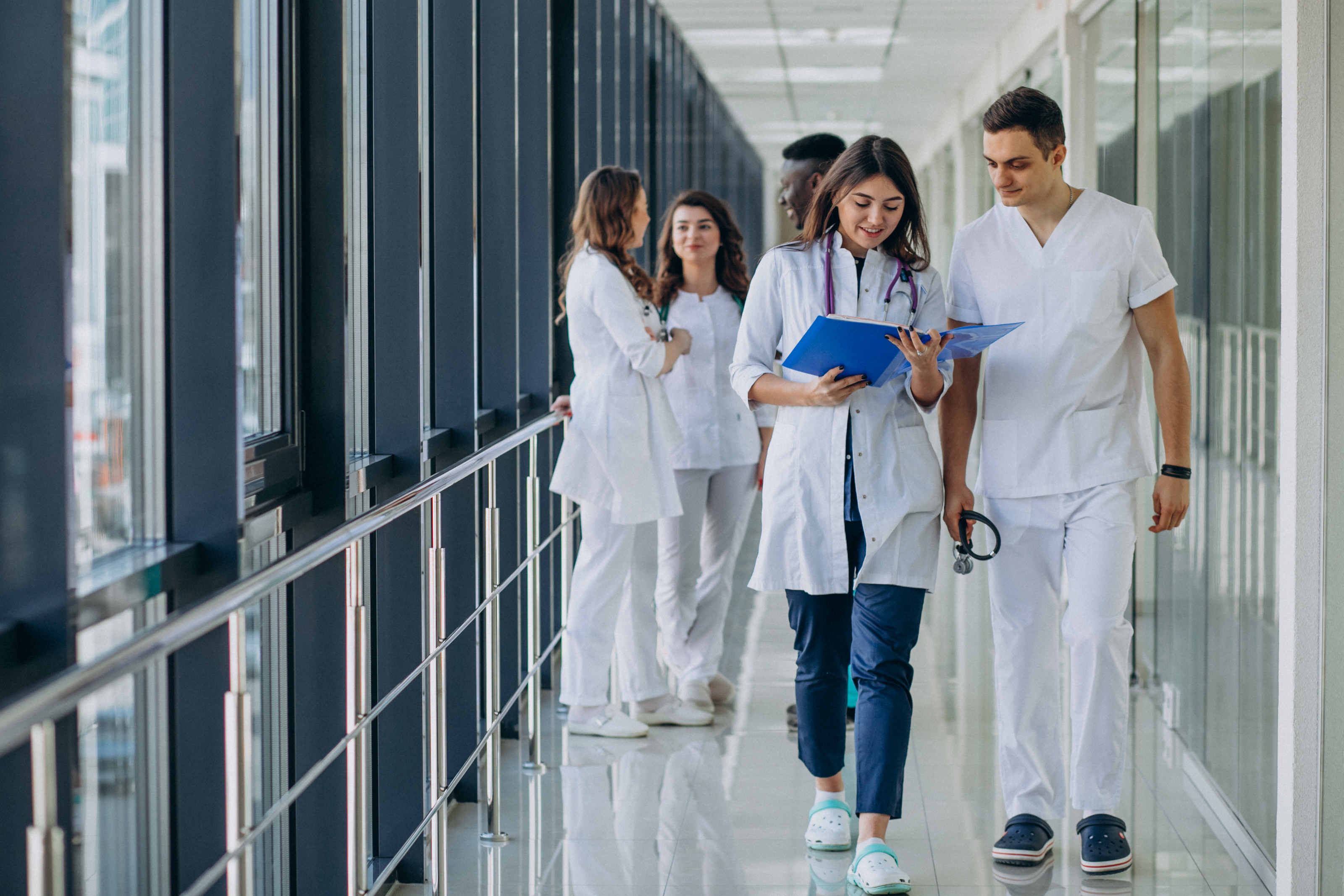 Two healthcare professionals walking down a hospital corridor in conversation.