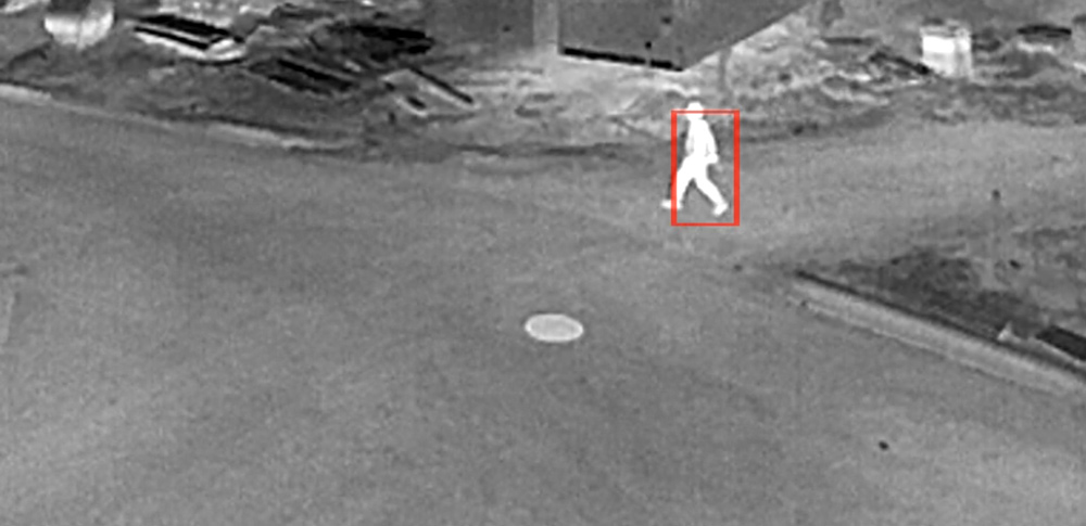 figure walking across job site on thermal camera with red identifying box surrounding them