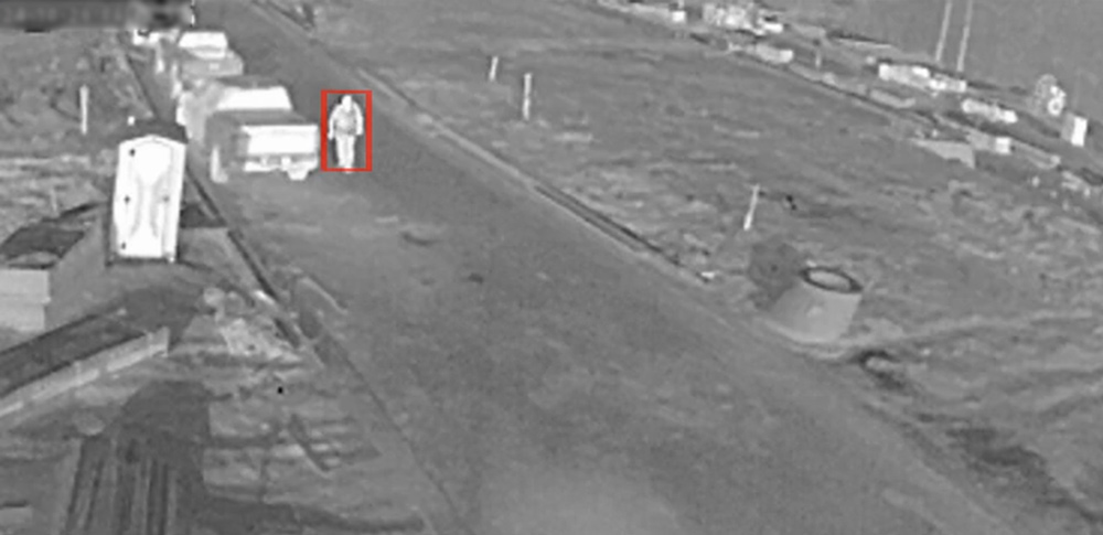 man walking in front of thermal camera on construction site from view of mobile security trailer