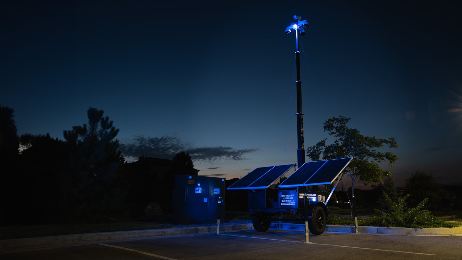 flashing blue lights in parking lot at night from mobile surveillance trailer