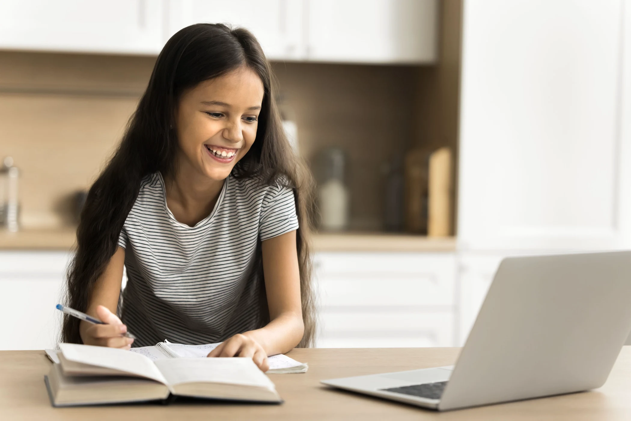 Smiling girl writing notes during an online lesson