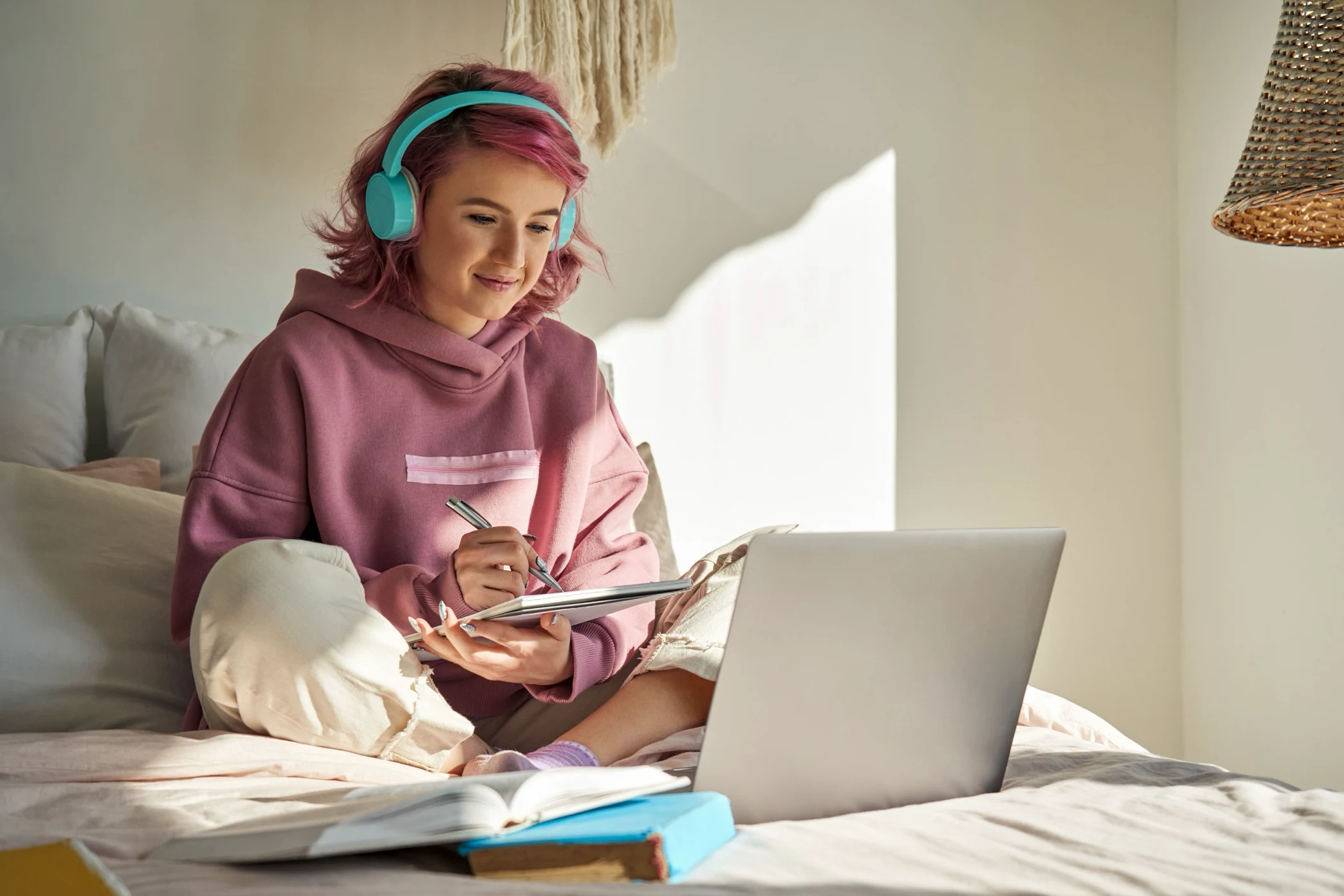 A-level student with headphones taking notes during an online lesson