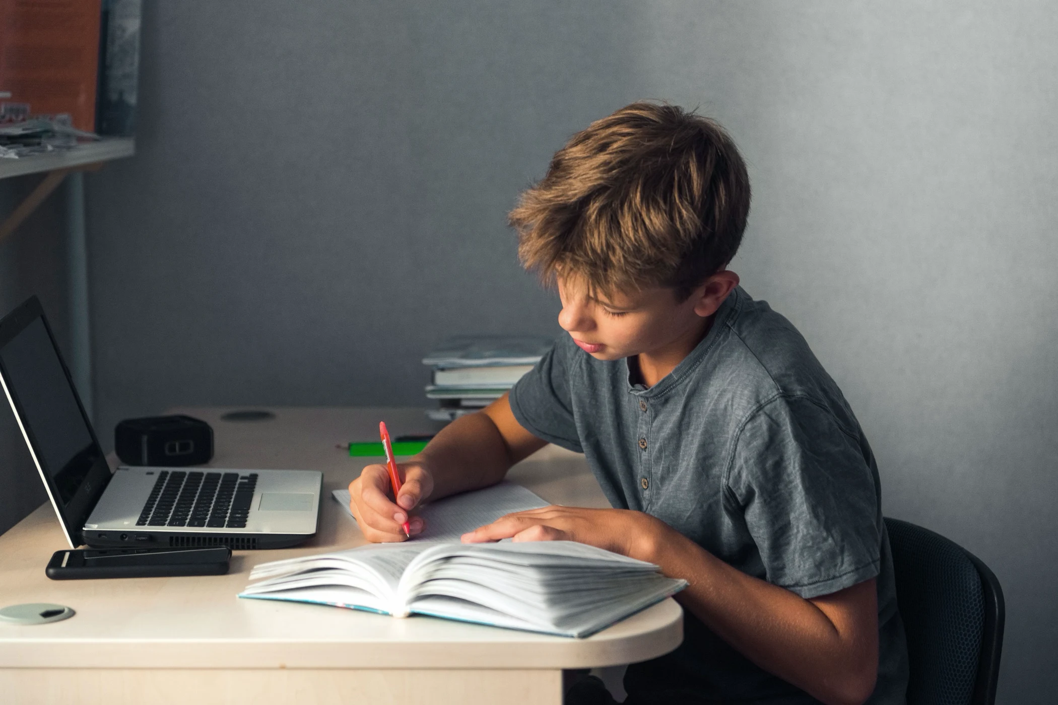 Secondary school student working through a textbook at his desk