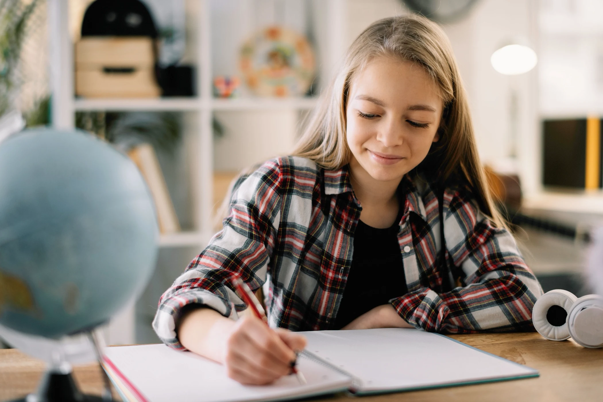 Girl smiling as she writes in her exercise book