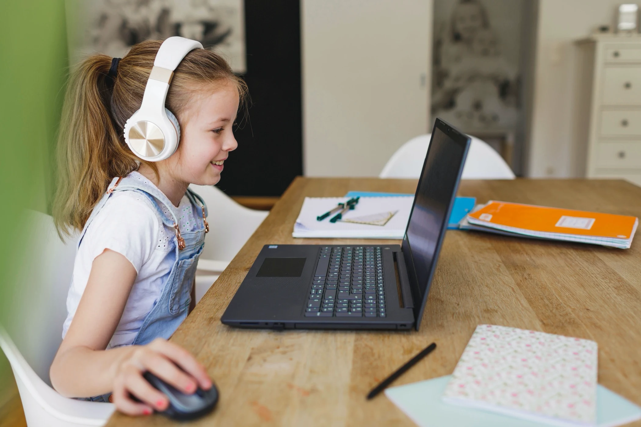 Primary-age girl with headphones in an online lesson on her laptop