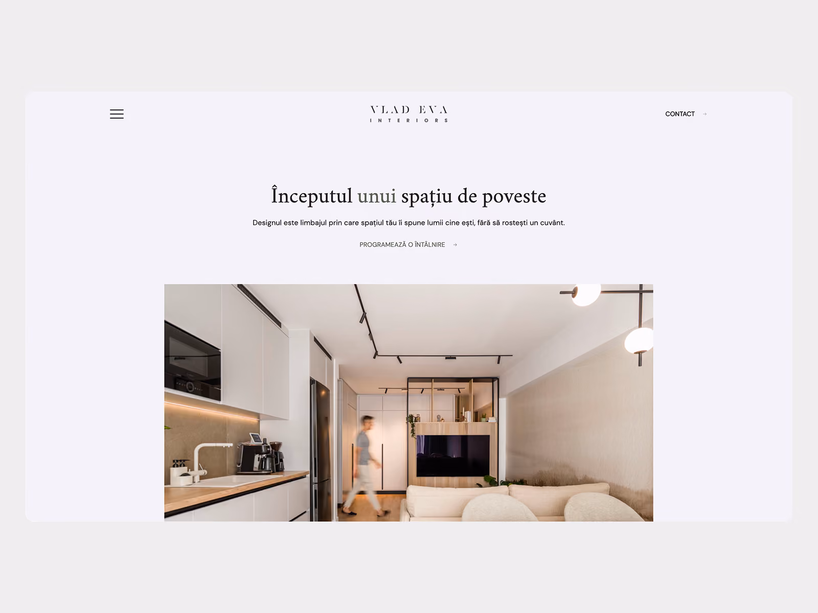 Website homepage for Vlad Eva Interiors featuring a modern, minimalist living space with a kitchen on the left, a person walking, and a cozy seating area on the right.