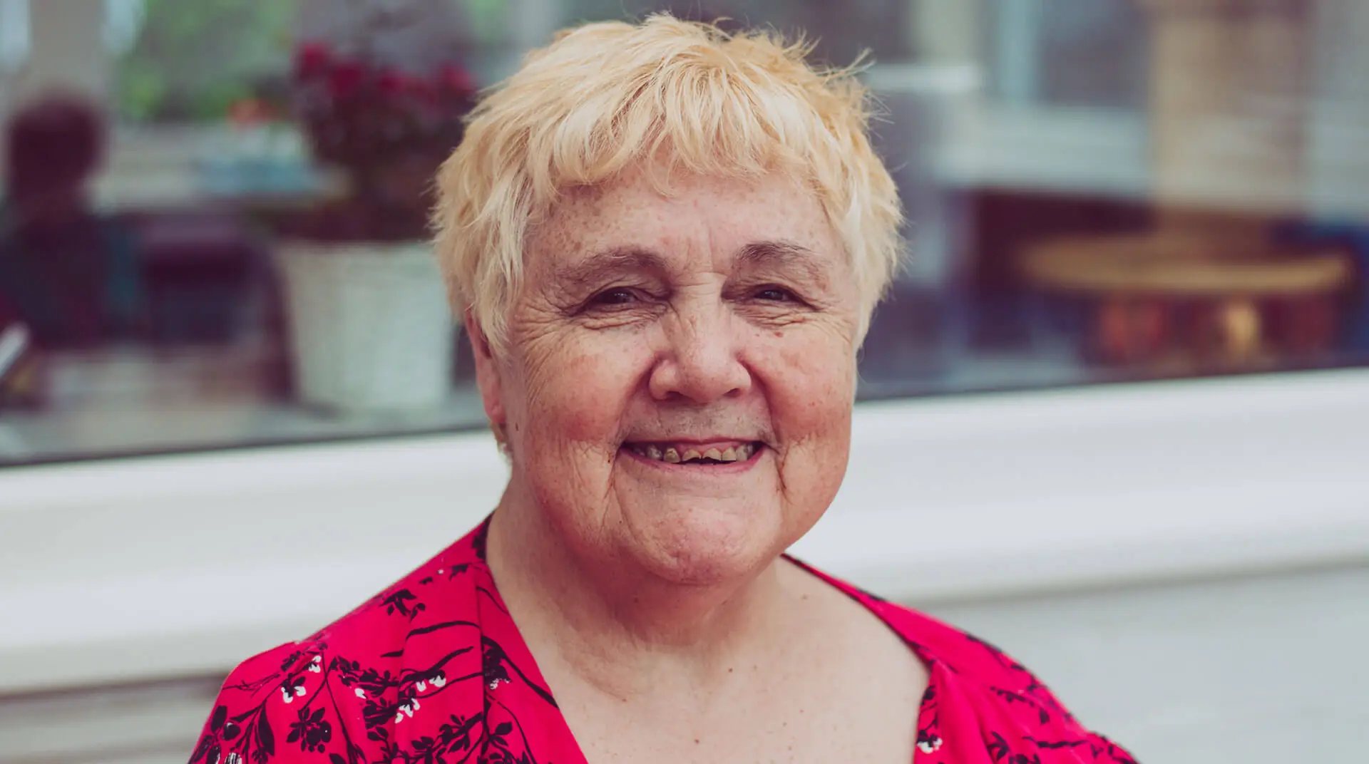 A smiling woman in a red patterned top, in a photograph supplied by Phoenix Care