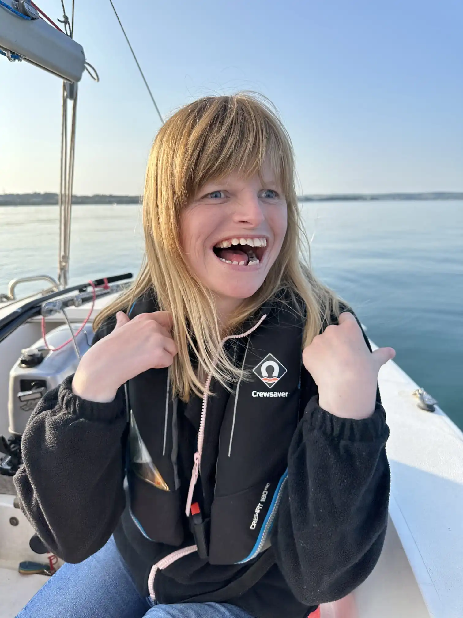 A woman wearing a lifejacket and enjoying a sailing trip