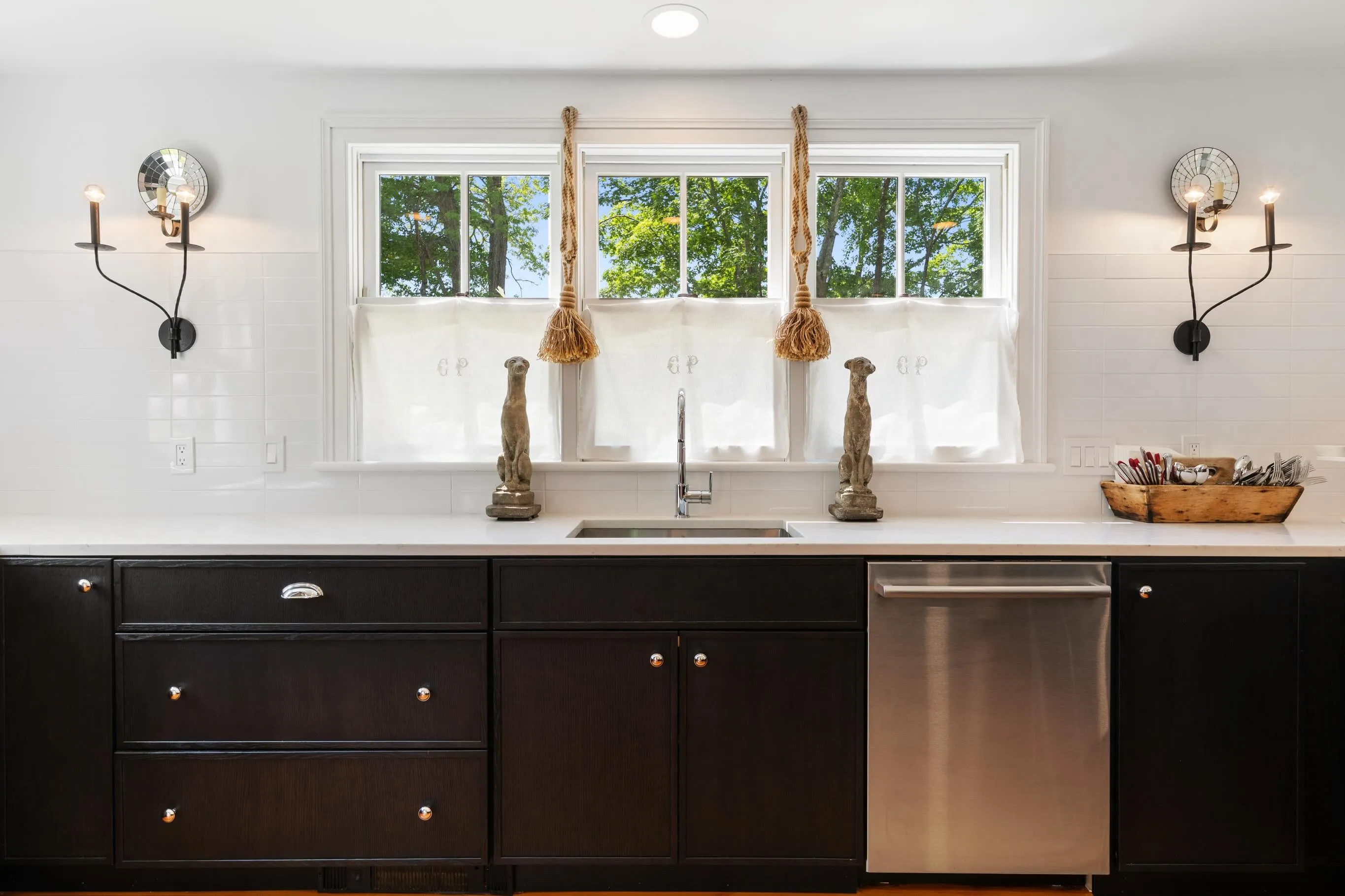 Black cabinetry and white counters beneath the curtained windows of the Black and Pine kitchen