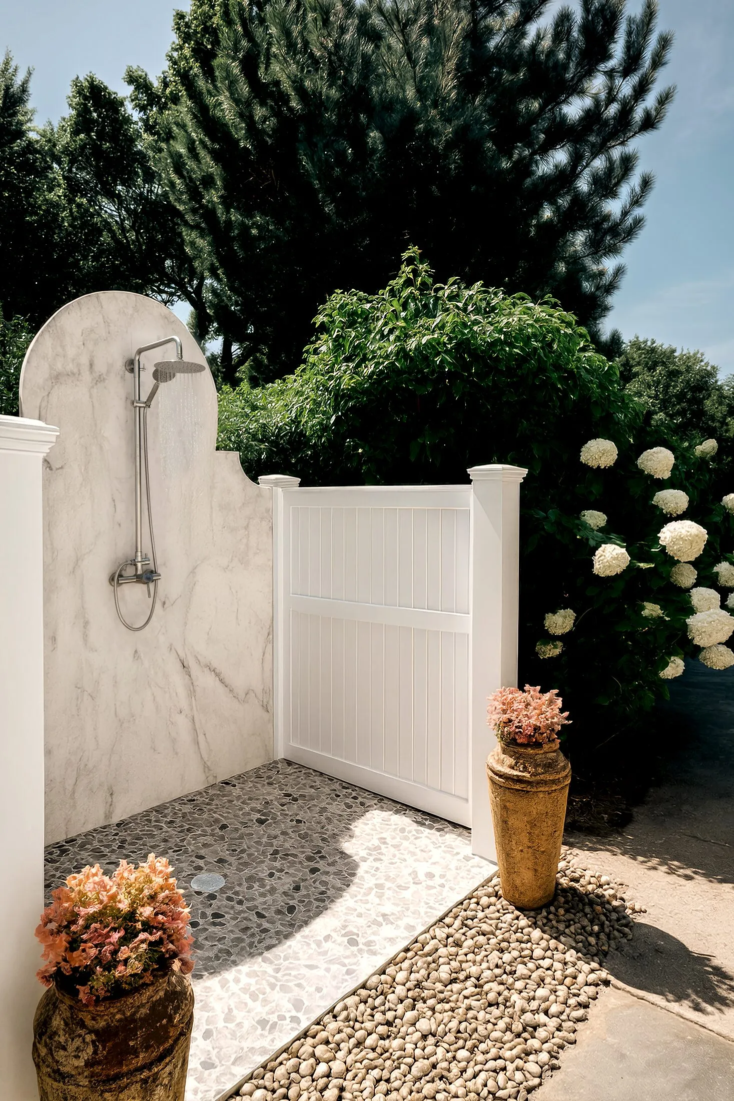 Marble outdoor shower set into a garden of hydrangea and pine