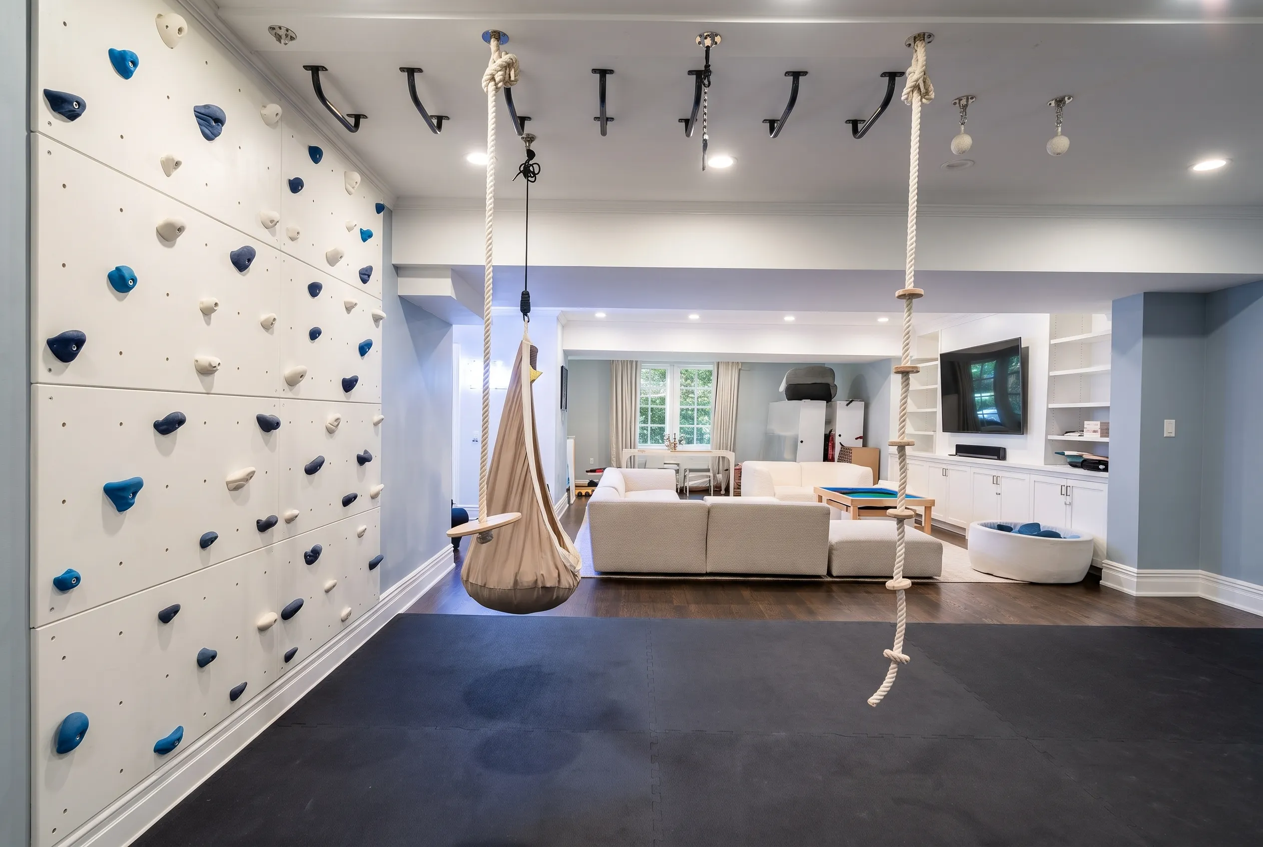 Climbing wall and rope swing in a finished lower-level playroom