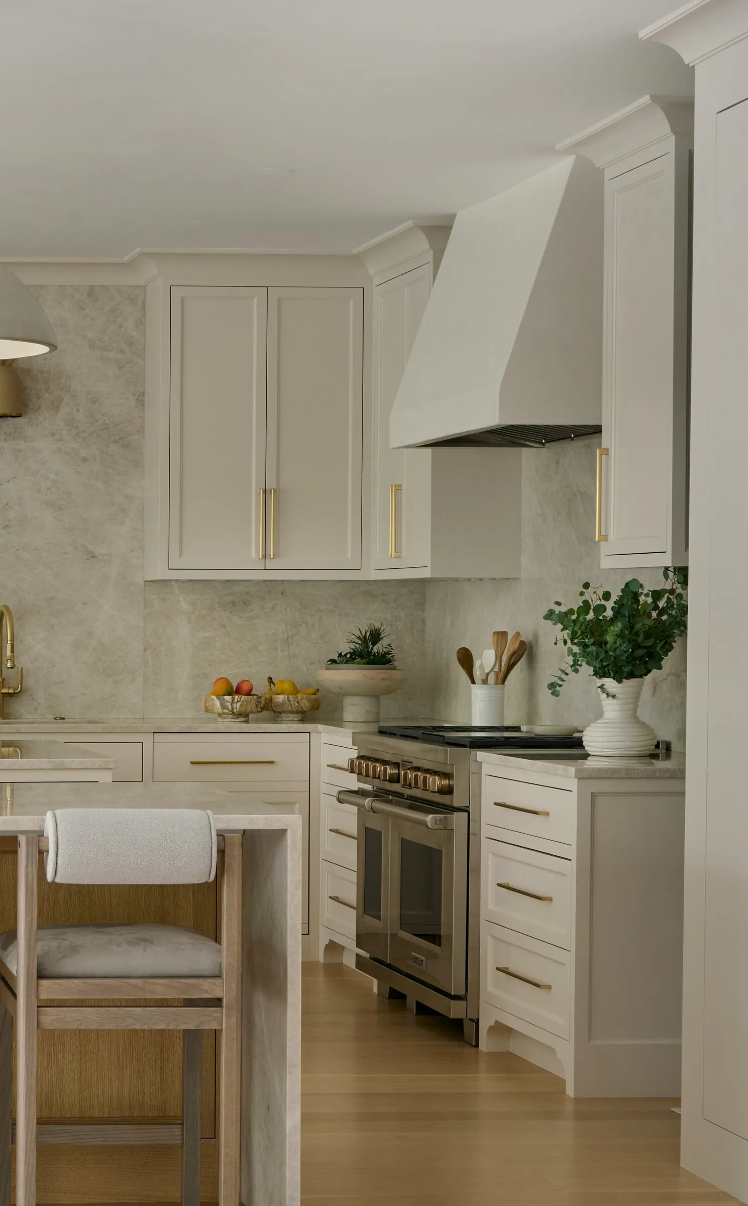 Plaster range hood above a stone backsplash in a cream kitchen