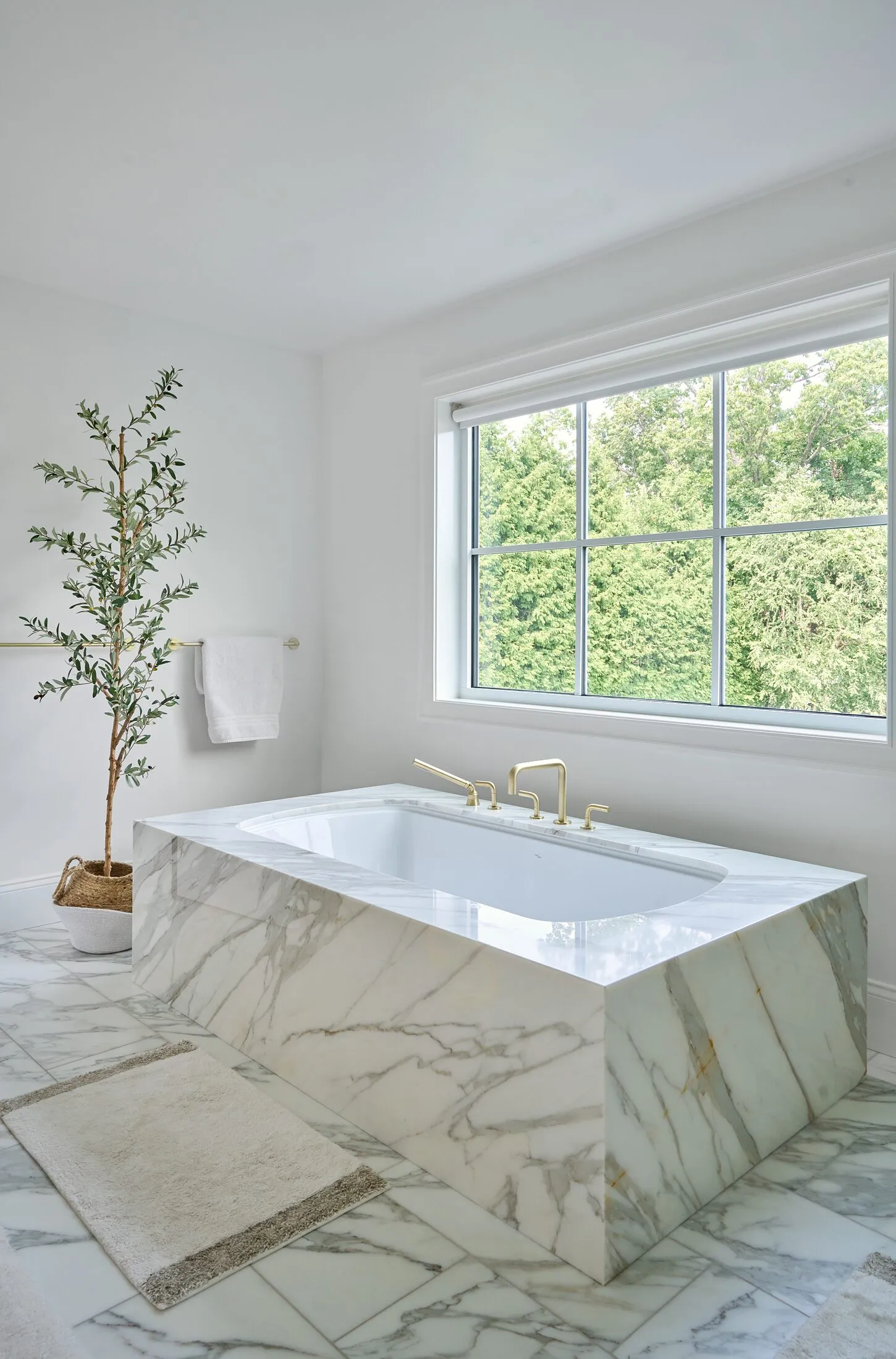 Freestanding tub clad in book-matched marble in a primary bath
