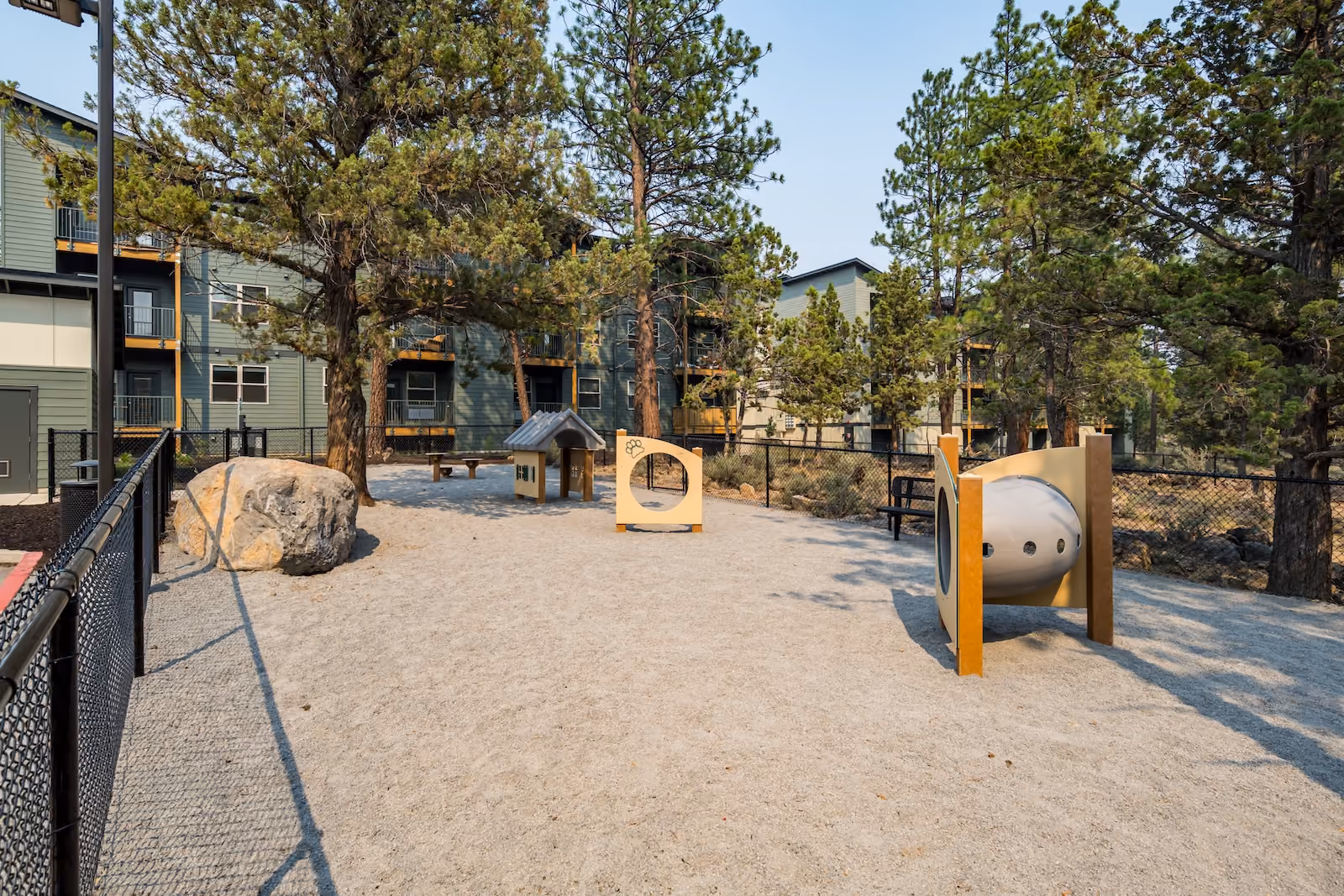 Dog park with tunnel, benches, and trees at The Veridian in Bend, Oregon