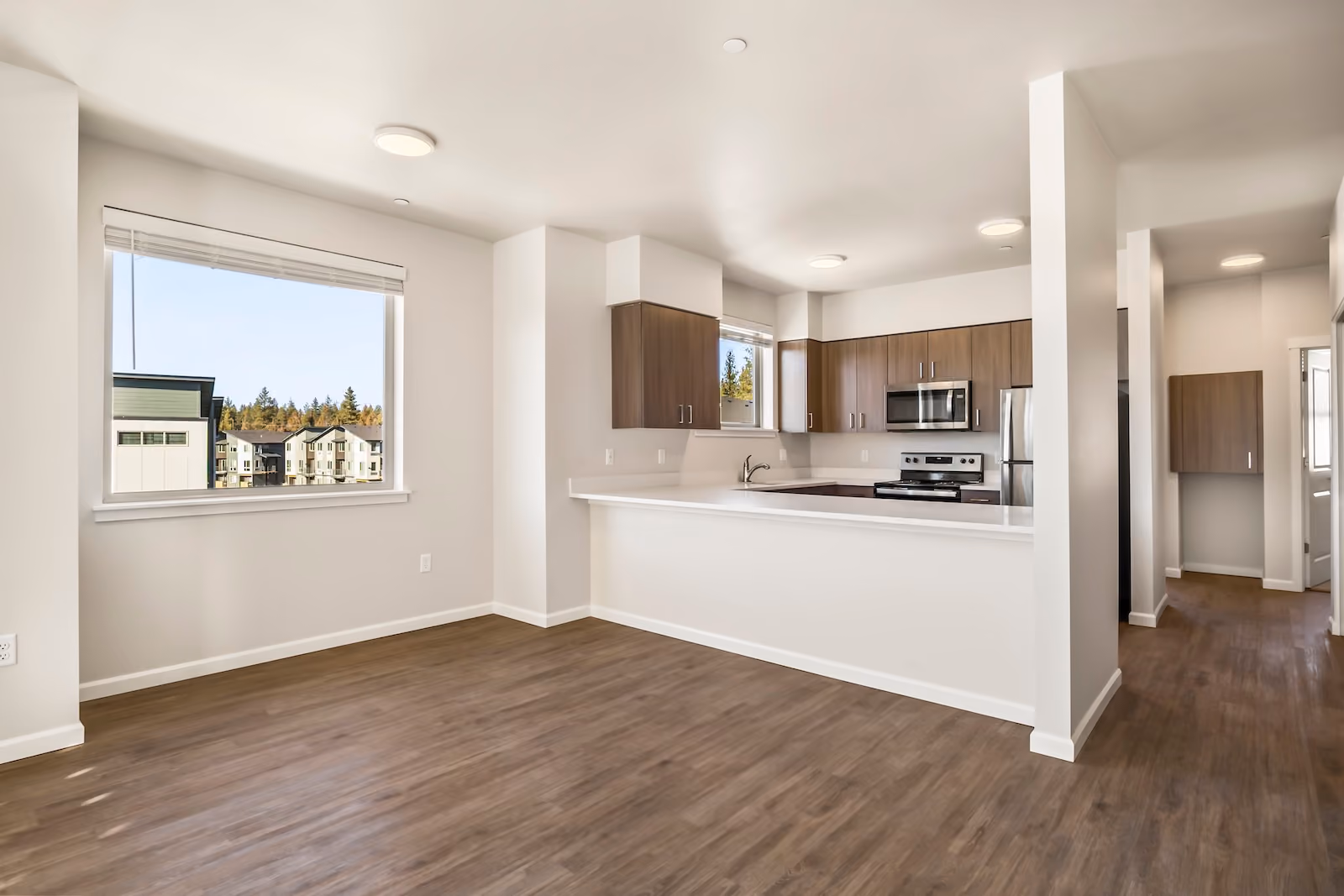 An open, vacant kitchen and living room area with polished hardwood floors at The Veridian in Bend, Oregon