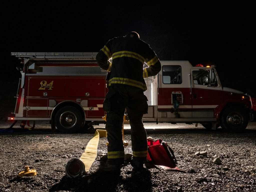 Firefighter gearing up beside Engine 24 at night