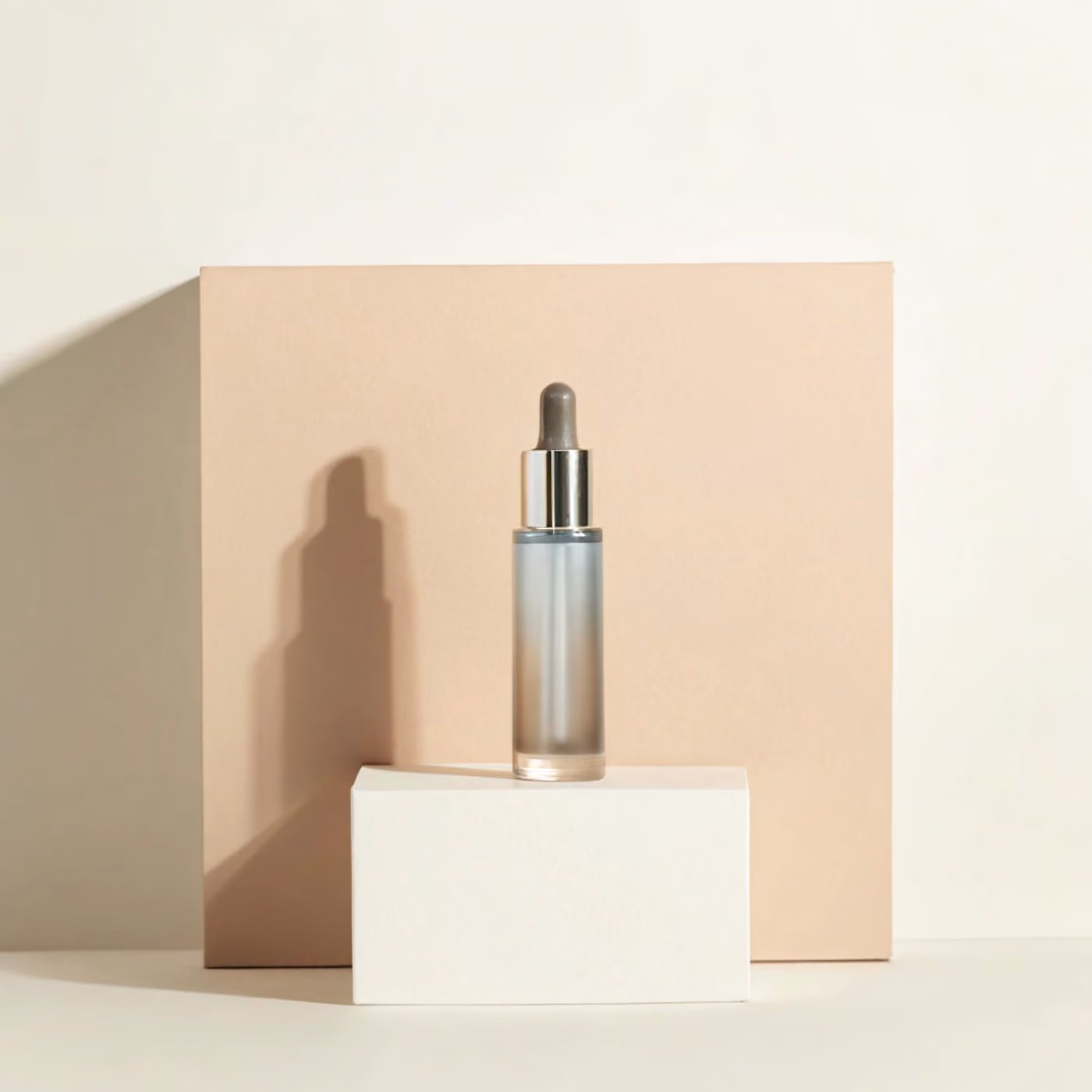 Serum bottle on a soft beige box in warm light