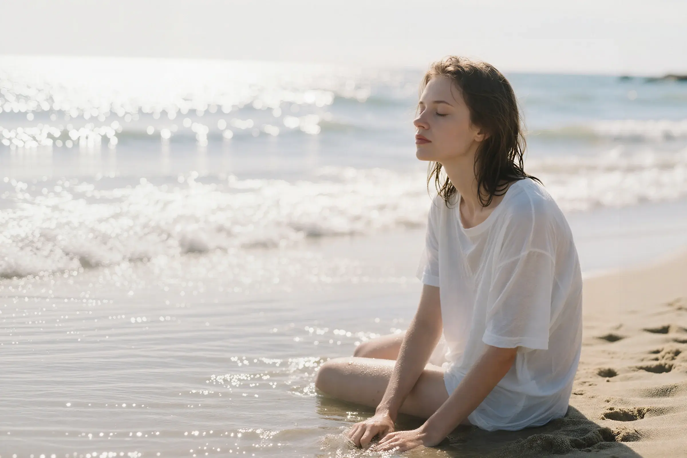Woman with wet hair sitting peacefully on a sunlit beach