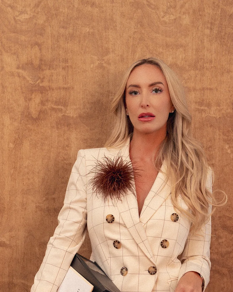 Sara Gullickson, founder of Duality & Co., in a cream tailored suit against burl wood.