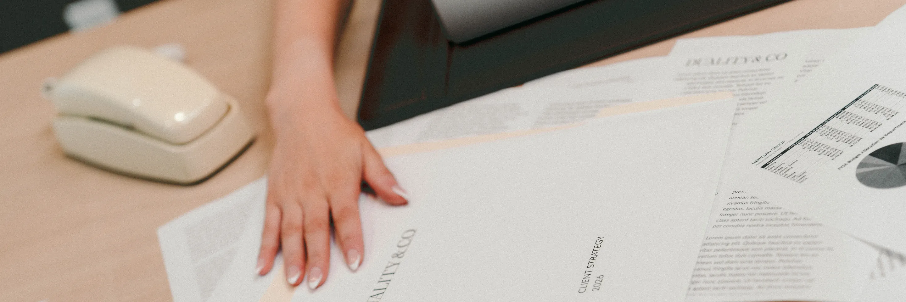A hand spreading Duality & Co. strategy papers across a desk beside a retro phone.