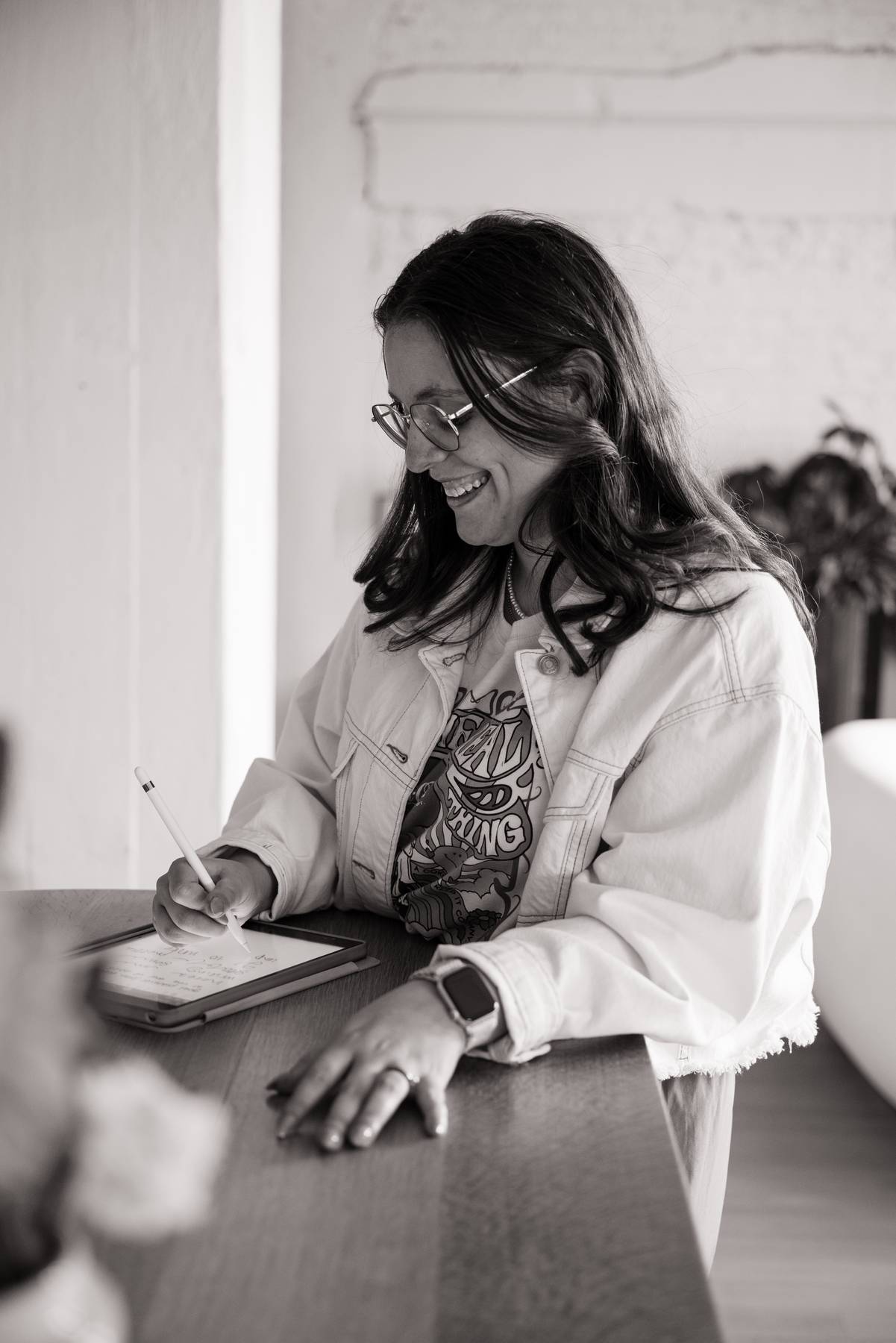 Molli at a table, writing on a tablet