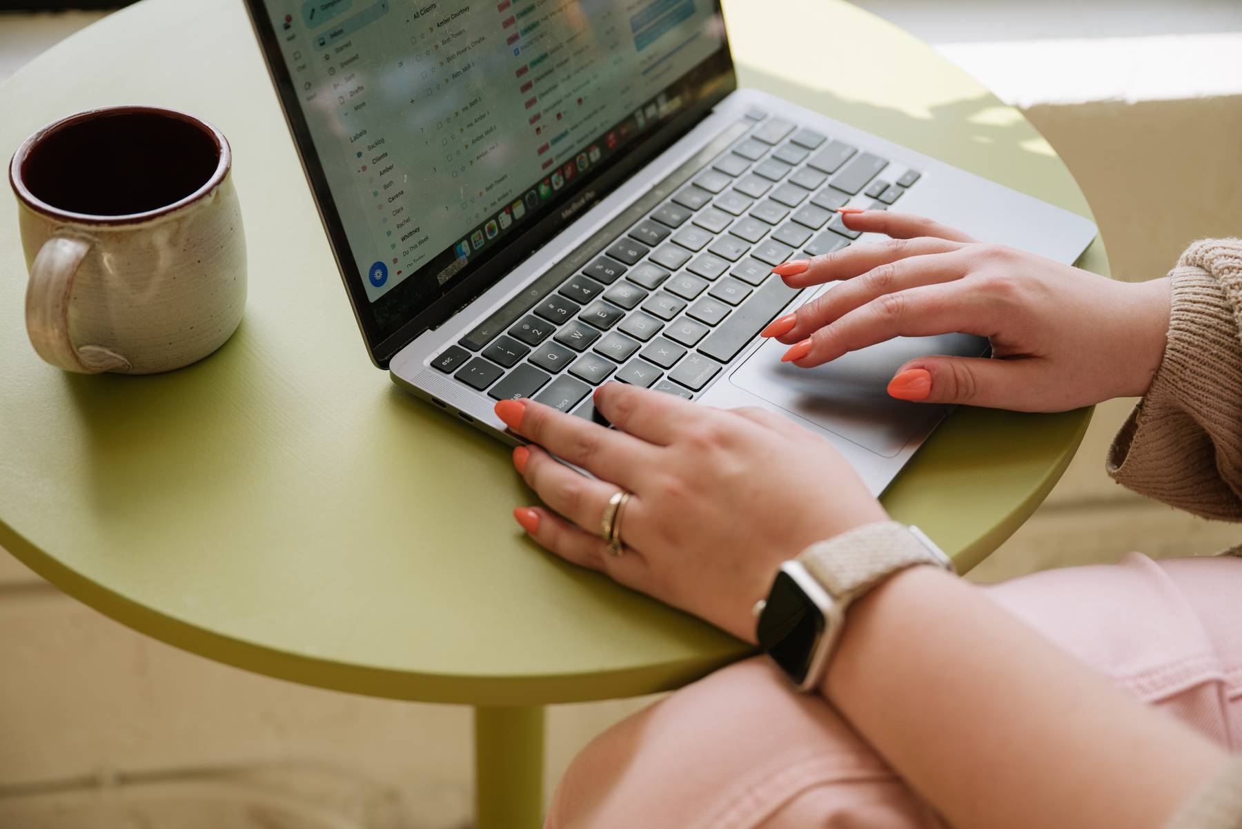 Molli's hands on her laptop at a café table