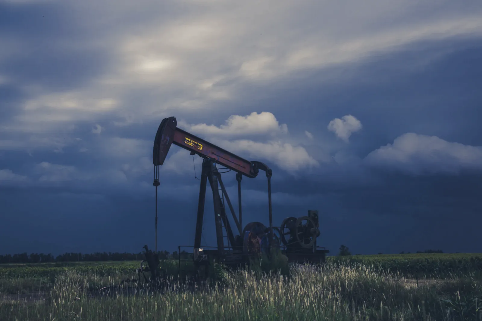 Pump jack on a producing oil field under a stormy sky