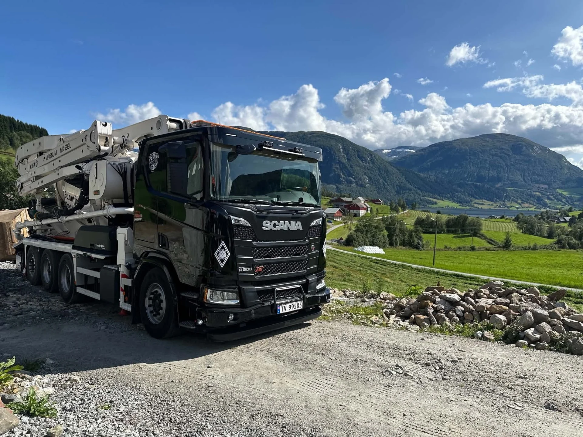 Sunnfjord Betongs pumpebil ved byggeplass med fjell i bakgrunnen