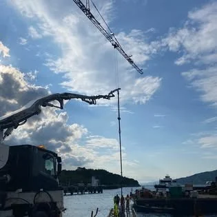 Betongpumpe med armen løftet mot himmelen