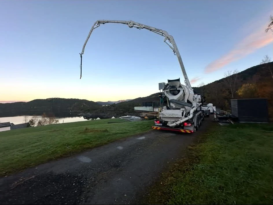 Betongpumpe i arbeid ved vannet i kveldslys
