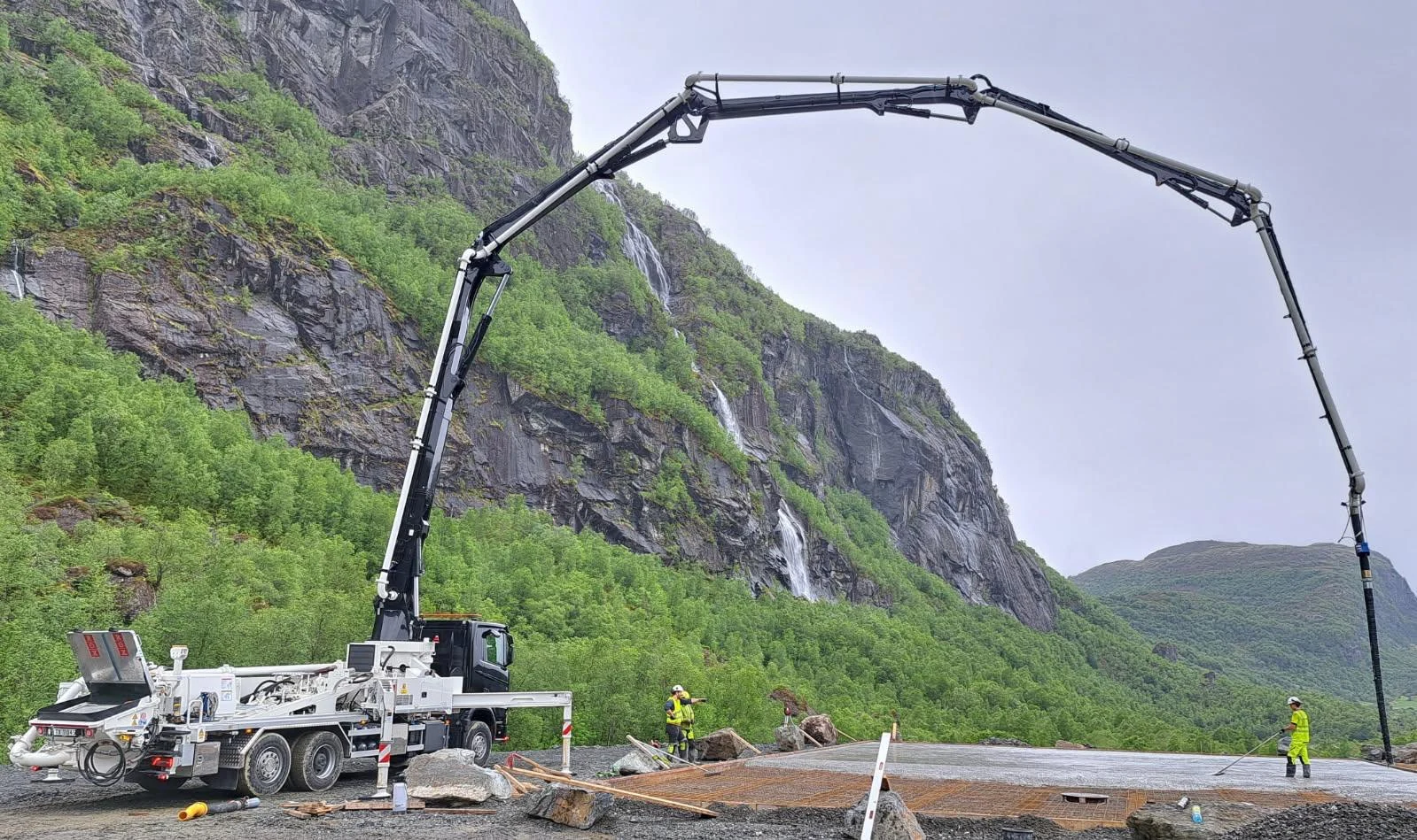 Betongpumpe med lang arm ved en fjellside