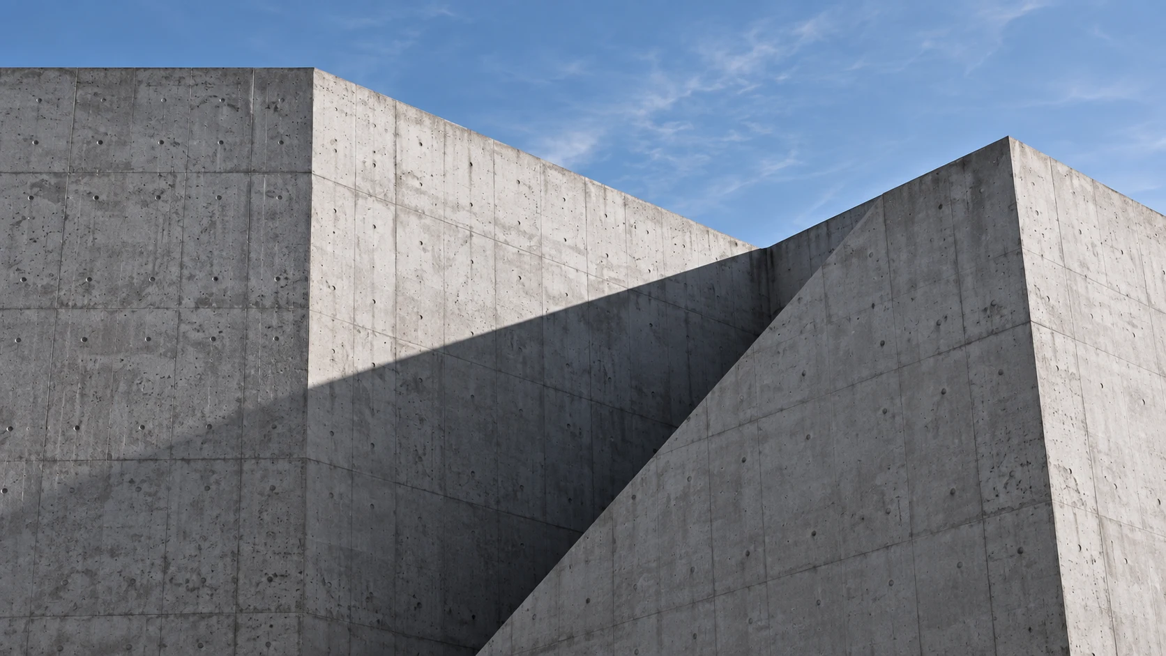 Arkitektoniske betongvegger med geometriske skygger mot en blå himmel. Illustrasjonsbilde.